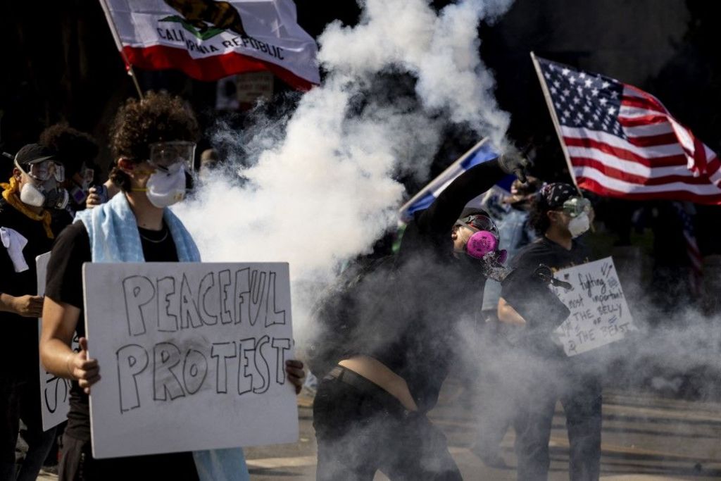 A protester in LA throws a tear canister back towards police