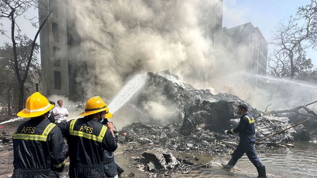 Firefighters tackle plumes of smoke at the scene of the crash