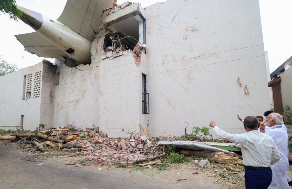 Narendra Modi looking up at the plane's tail that is crashed into a building.